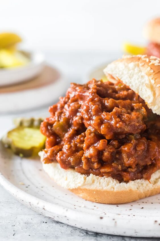 how to make classic sloppy joes with ketchup, open faced sloppy joe sandwich on a small white plate served with pickle slices