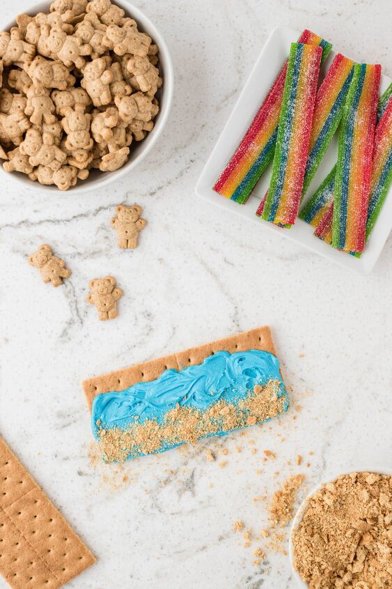 how to make beach day graham crackers, placing crushed graham cracker onto blue frosting
