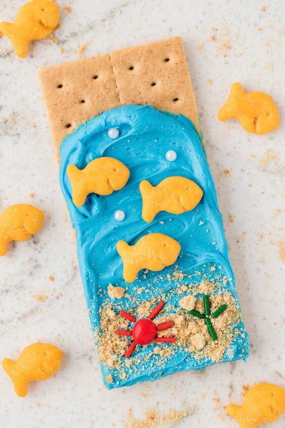 make ocean themed graham cracker snacks for a fun day, ocean graham cracker with blue frosting fish crackers and sprinkles