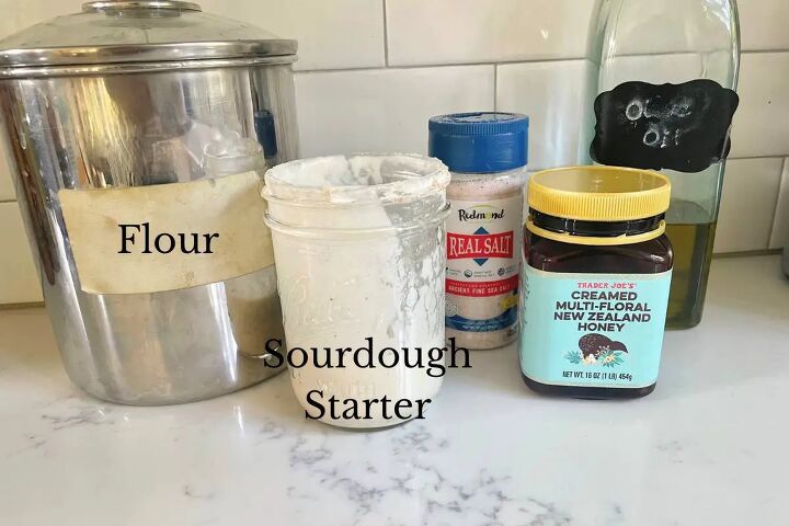 easy perfect sourdough focaccia recipe, flour jar of sourdough starter salt honey and olive oil on kitchen counter