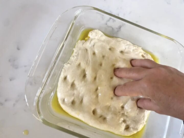 easy perfect sourdough focaccia recipe, fingers pressing dimples into surface of sourdough focaccia