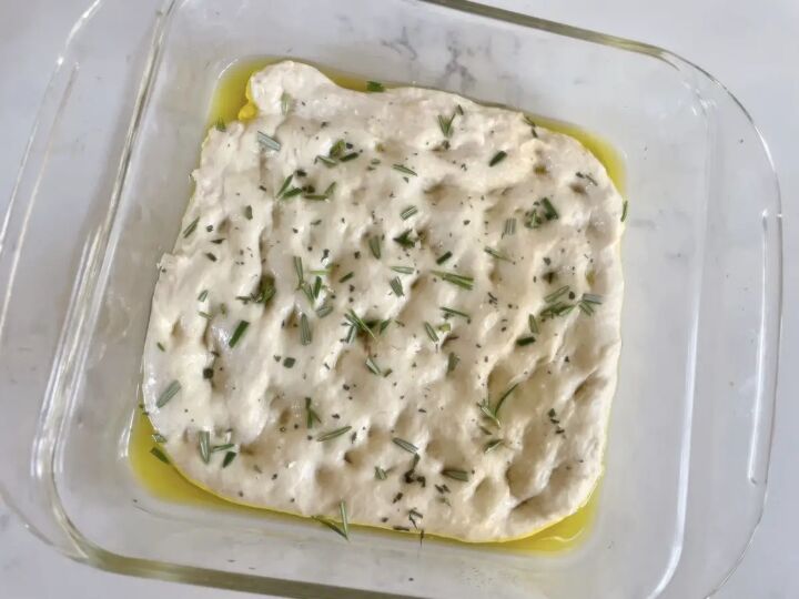 easy perfect sourdough focaccia recipe, sourdough focaccia sprinkled with chopped rosemary and olive oil in square glass baking dish