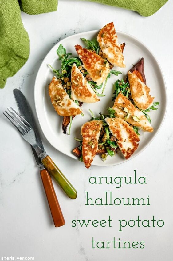 arugula and halloumi tartines on sweet potato toast, sweet potato toasts topped with arugula and halloumi on a white plate next to vintage flatware