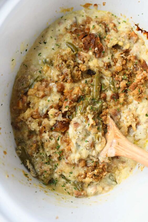 the best slow cooker chicken and stuffing, A wooden spoon in a white slow cooker with chicken and stuffing