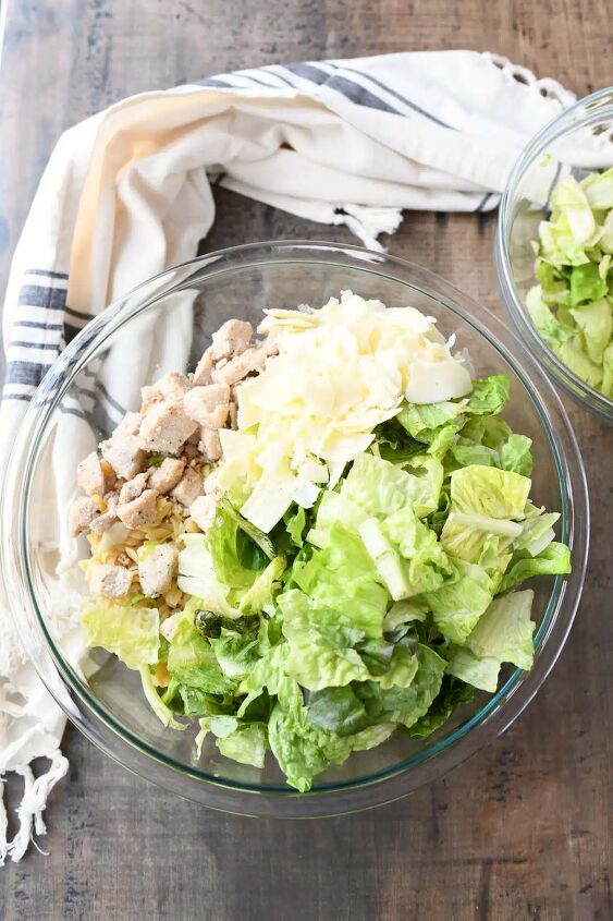 chicken caesar pasta salad, Romaine shaved parmesan and chicken in a glass bowl