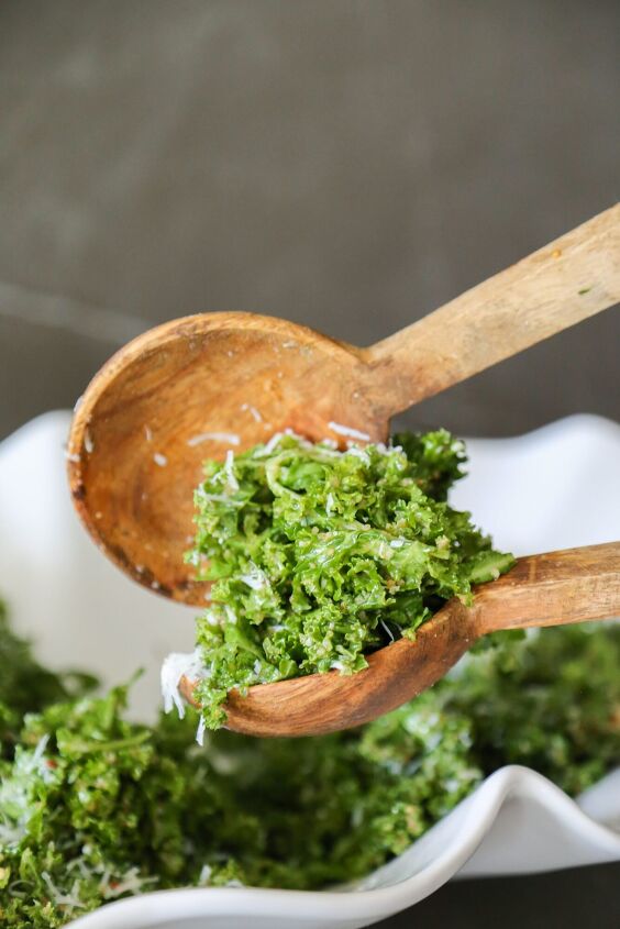 true food kale salad recipe copycat, true food kale salad in a bowl getting scooped out with wooden spoons