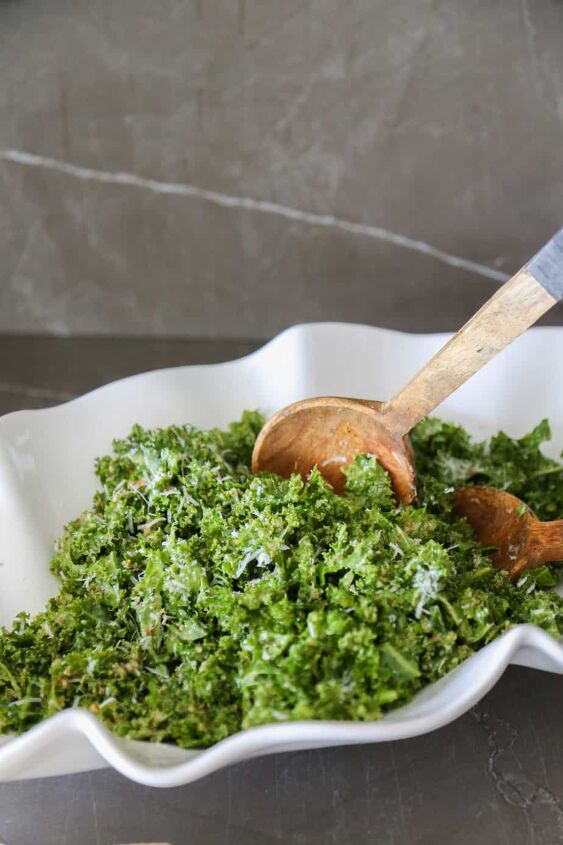 true food kale salad recipe copycat, true food kale salad in a bowl getting scooped out with wooden spoons
