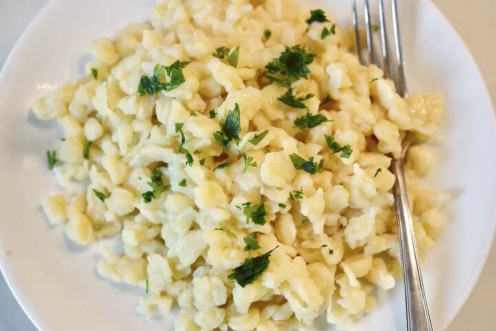 homemade german egg noodles spaetzle, German spaetzle with chopped parsley on white plate with fork