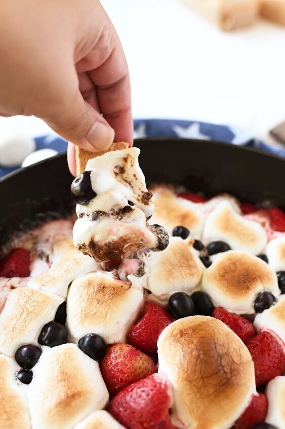 epic s mores berry skillet dip, A hand dipping into gooey marshmallow