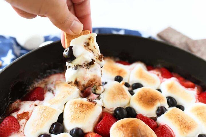 epic s mores berry skillet dip, A hand dipping into berry smores dip