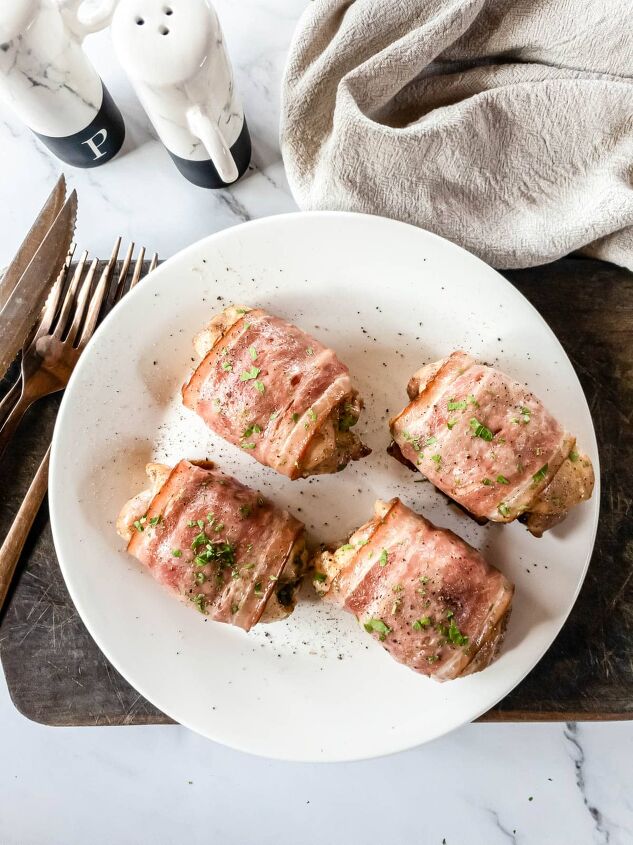 bacon wrapped chicken thighs in the oven so easy, Four chicken thighs on plate on cutting board with cloth