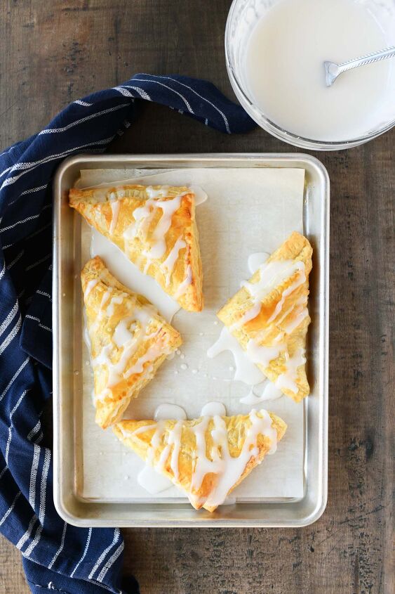 iced lemon turnovers, Iced turnovers on a parchment lined baking sheet