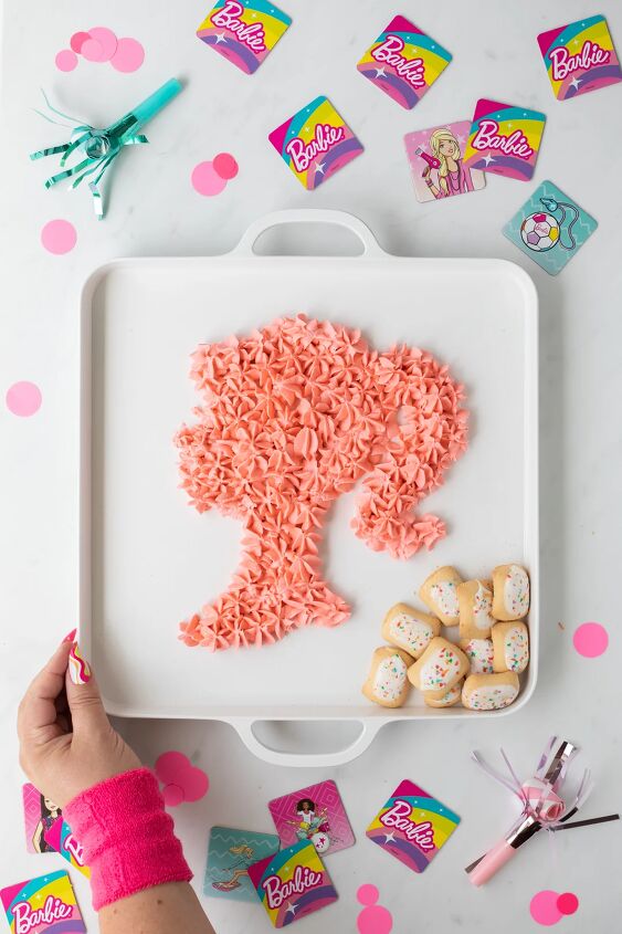 come on let s make barbie dessert dip, woman with neon pink wristband holding barbie inspired dessert tray shaped like barbie logo silhouette