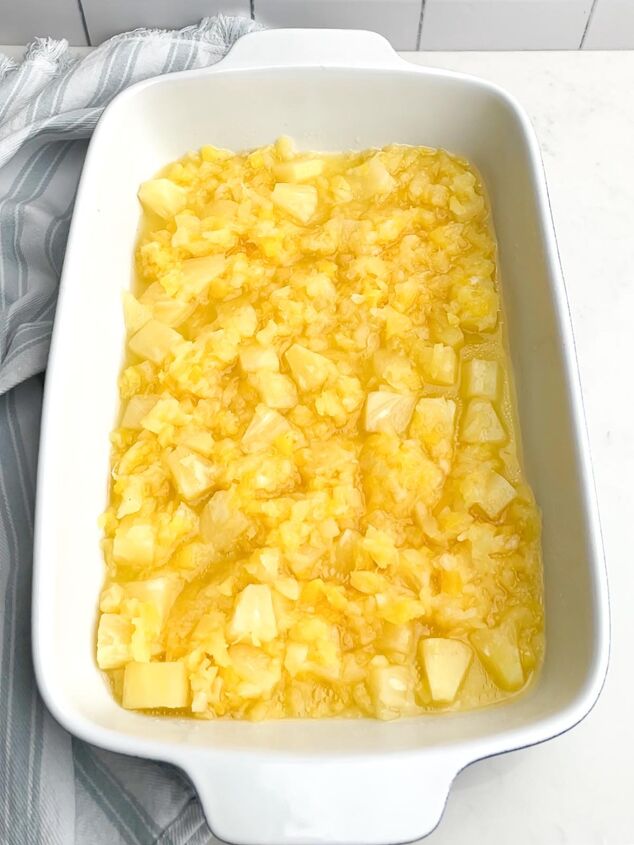 the best pineapple dump cake super easy, pineapple chunks and pineapple tidbits in a white baking dish