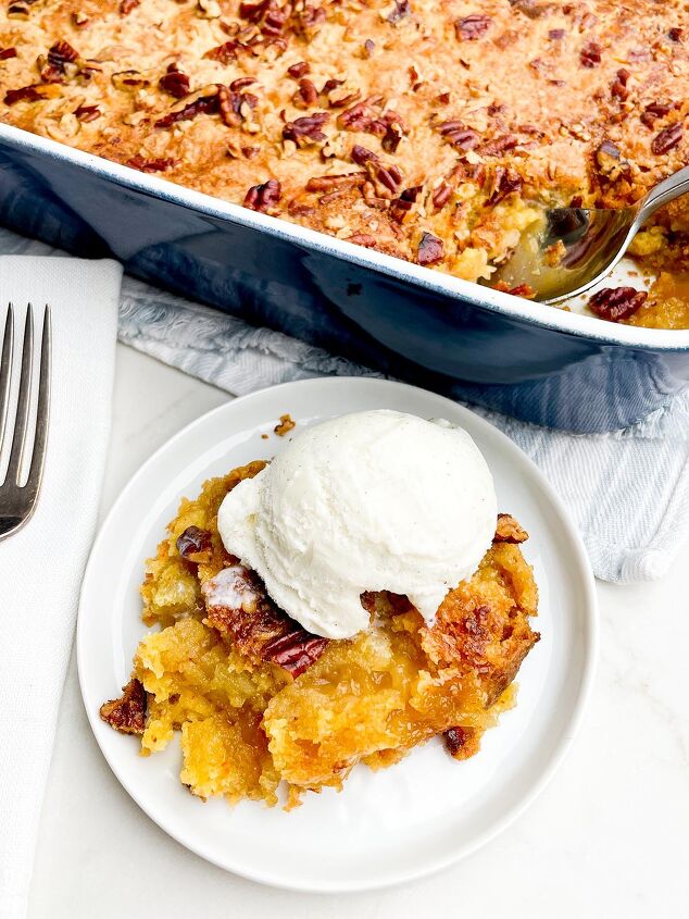 the best pineapple dump cake super easy, pineapple dump cake and ice cream on a white plate with pan of dump cake in background