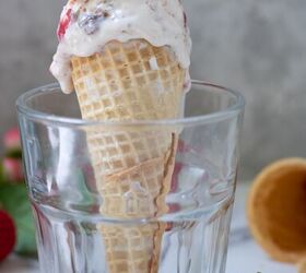 A short glass with an ice cream cone in it There s ice cream dripping down the sides you can see more ice cream cones and a strawberry in the background