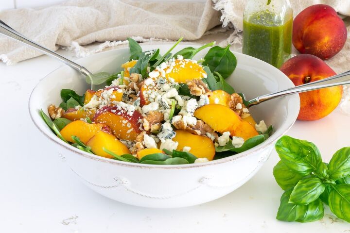 spinach and nectarine salad with basil dressing, Spinach and Nectarine Salad in a white bowl with nectarines basil and basil vinaigrette in the background