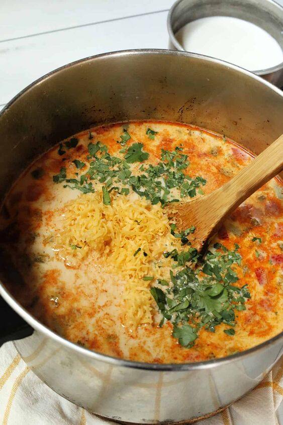 creamy mexican bean soup with corn, Adding shredded cheddar cheese to a pot of soup