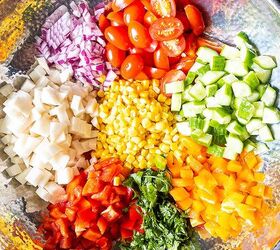 Ingredients for an easy corn salad recipe diced jicama red bell pepper orange bell pepper cucumber red onion halved grape tomatoes and chopped cilantro in a steel bowl
