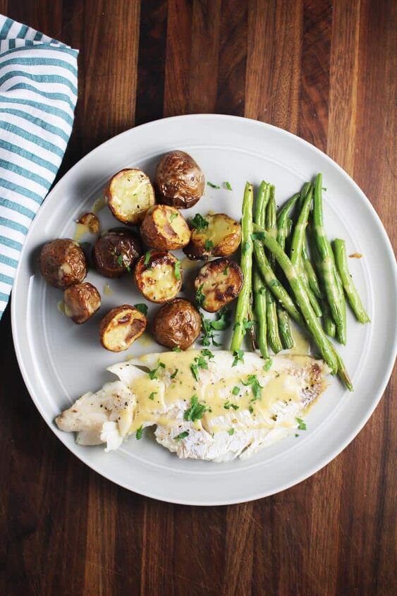 sheet pan dinner with fish and brown butter sauce, overhead view of a plate of fish green beans and potatoes from a sheet pan dinner