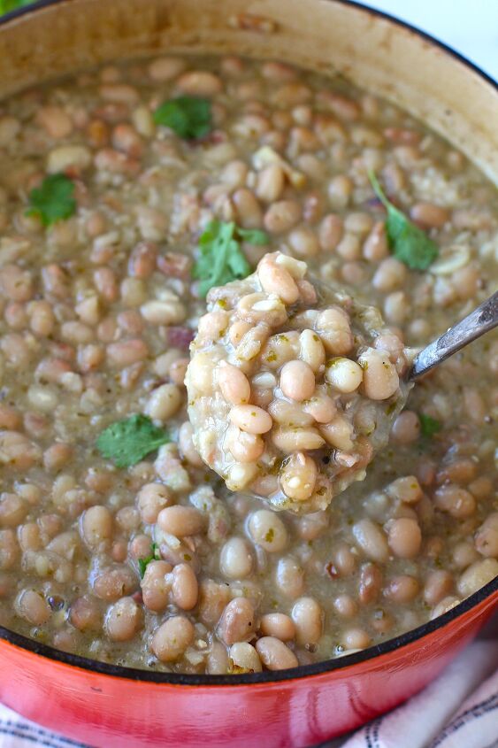 carioca beans dutch oven pinto beans, Spoon scooping up Carioca beans from a pot of beans with cilantro leaves on top