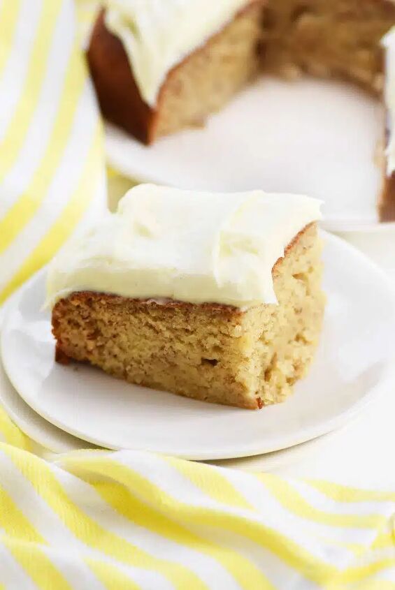 easy banana cake with maple cream cheese frosting, Frosted banana cake on white dish with yellow linen towel