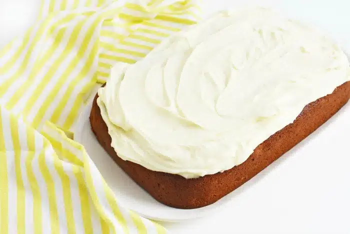 easy banana cake with maple cream cheese frosting, Maple Frosted Banana Cake on a white table with striped yellow napkin