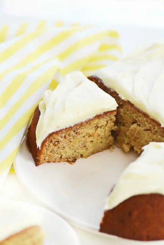 easy banana cake with maple cream cheese frosting, Maple banana cake in slices on a white platter with yellow striped napkin