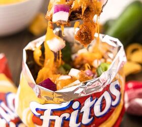 no plate needed when you make walking frito pie, fritos pie recipe served in corn chips bag with fork taking a bite out