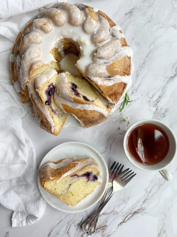 bonne maman blueberry swirl bundt cake, Bonne Maman Blueberry Swirl Bundt Cake on a platter and a plate with a cup of tea