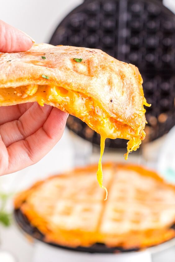 easy quesadilla in waffle maker, Quesadilla slice in hand with melted cheese dripping out
