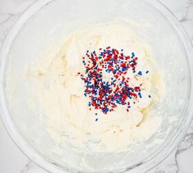 red white and blue cheesecake dip recipe, Cream cheese and sprinkles being mixed in a bowl