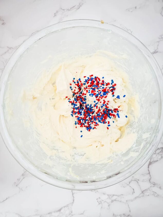 red white and blue cheesecake dip recipe, Cream cheese and sprinkles being mixed in a bowl