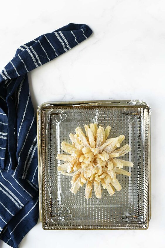 make an air fryer onion blossom at home, A battered blooming onion in an air fryer tray