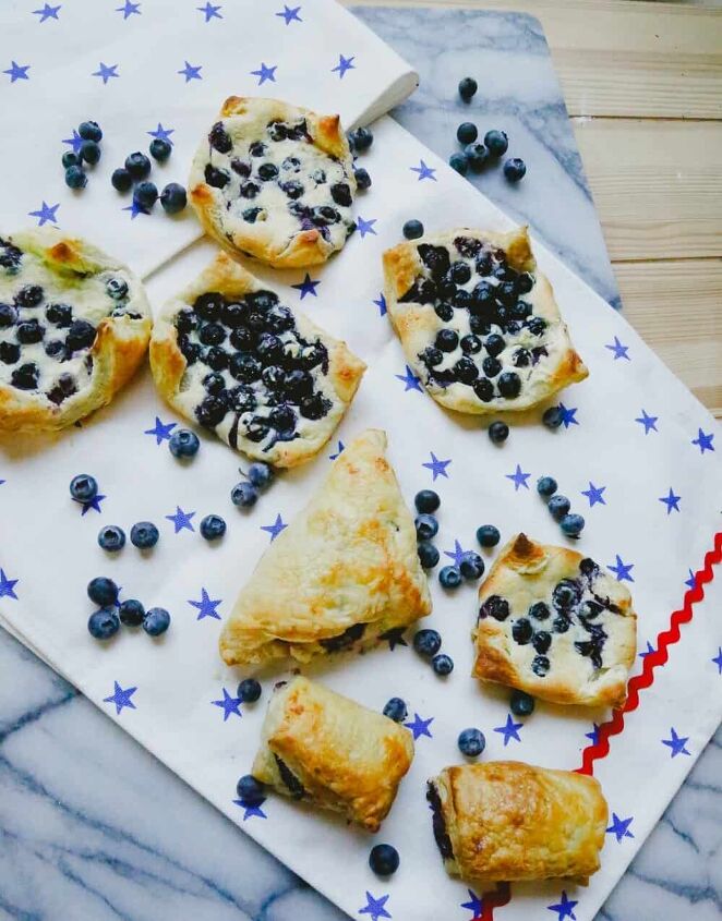 easy blueberry puff pastry turnovers, Fourth of July setting with baked fruit turnovers sitting on a marble back drop