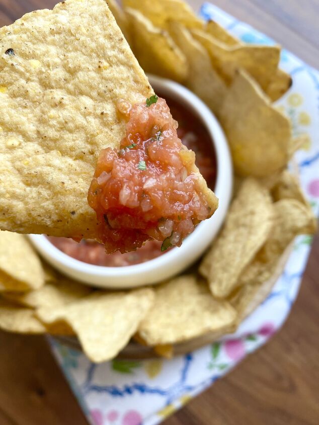 pineapple blender salsa, Close up of tortilla chip with salsa on it with bowl of chips and salsa in the background