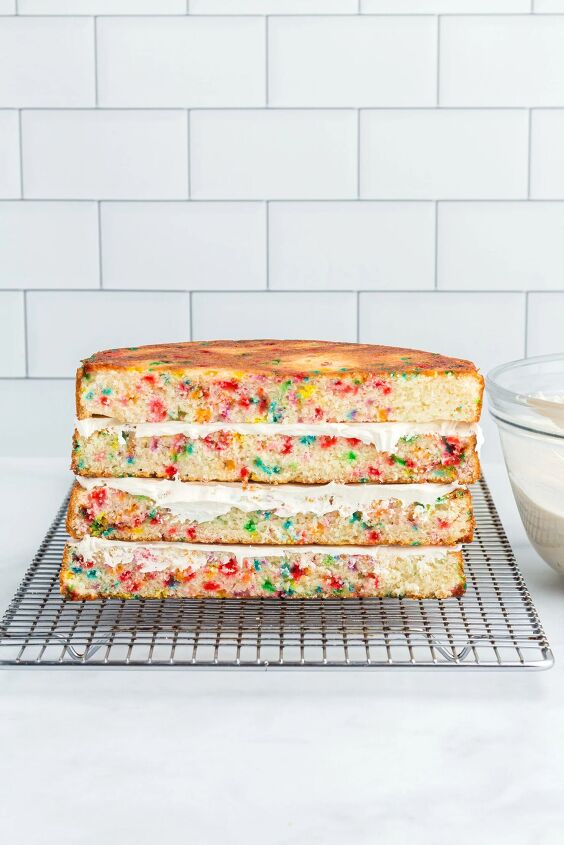 how to make a funfetti rainbow cake perfect for every celebration, cake halves stacked with frosting layers