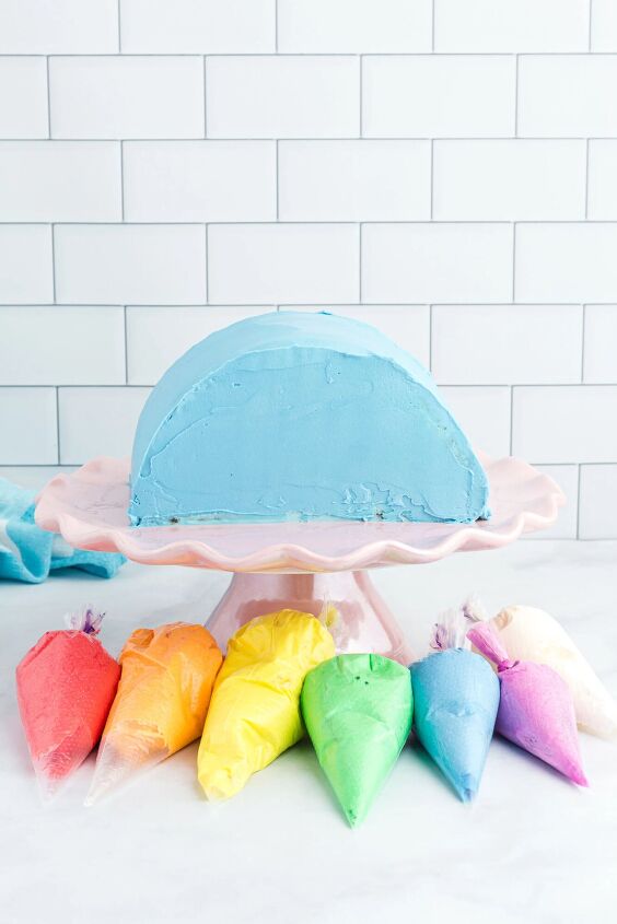 how to make a funfetti rainbow cake perfect for every celebration, preparing to add rainbow colored frosting to blue frosted rainbow shaped cakes