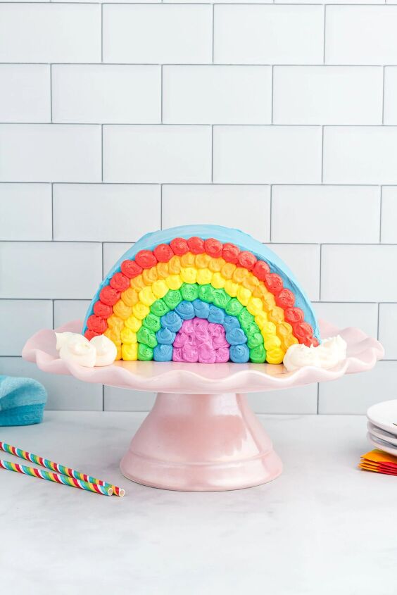 how to make a funfetti rainbow cake perfect for every celebration, pretty rainbow cake with frosting set on a pretty cake stand