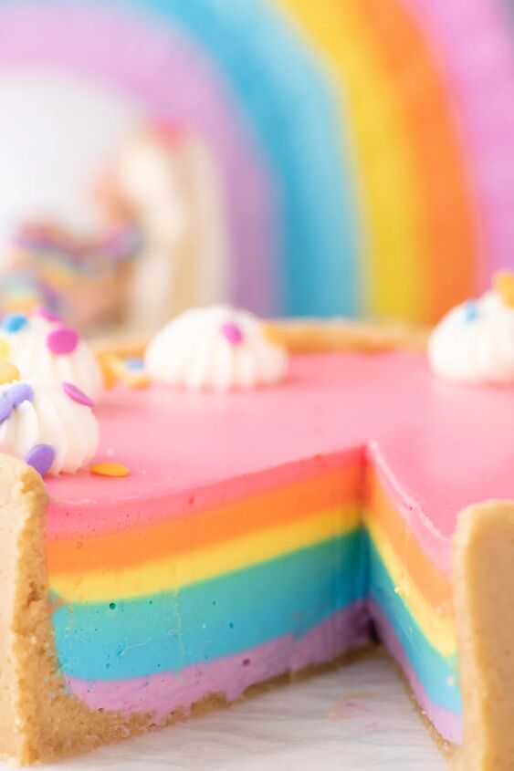 how to make a funfetti rainbow cake perfect for every celebration, slice removed from rainbow cheesecake to reveal pretty colored layers