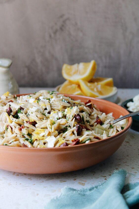 pasta salad with sun dried tomatoes green olives provolone, lemon orzo pasta salad in a red bowl