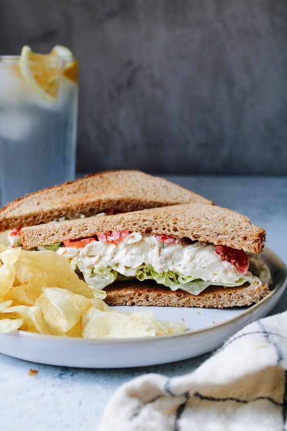 curry chicken salad with grapes, sideview of the best chicken salad sandwich on wheat bread with butter lettuce and tomatoes