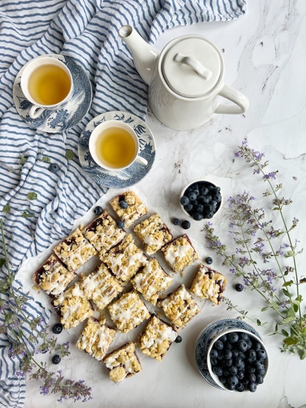 blueberry crumb bars, blueberry crumb bars with glaze and 2 cups of tea and a teapot