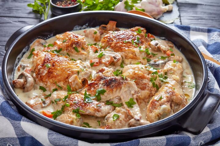 the best texas chicken portobello mushroom recipe, hot chicken in a black dutch oven on a black table chicken meat browned and stewed in white wine cream sauce with mushrooms and vegetables