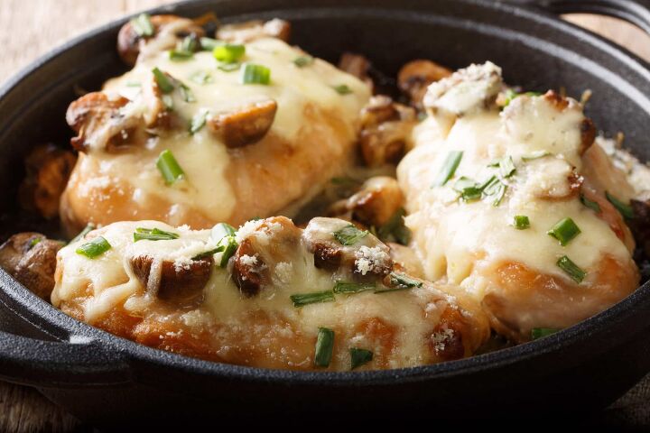 the best texas chicken portobello mushroom recipe, hot chicken in a black dutch oven on a black table chicken meat browned and stewed in white wine cream sauce with mushrooms