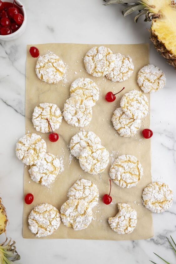 need a vacation try these pineapple cake mix cookies now, pineapple cookies spread on brown parchment paper with maraschino cherry garnish