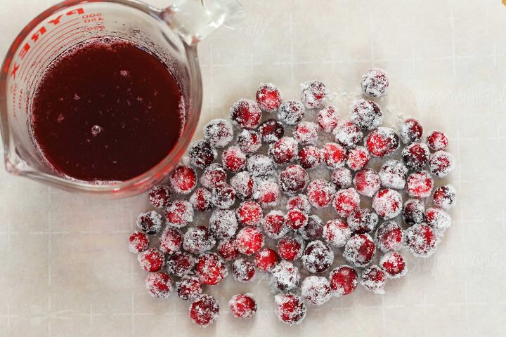 cranberry mimosa, cranberry syrup next to sugared cranberries on parchment paper