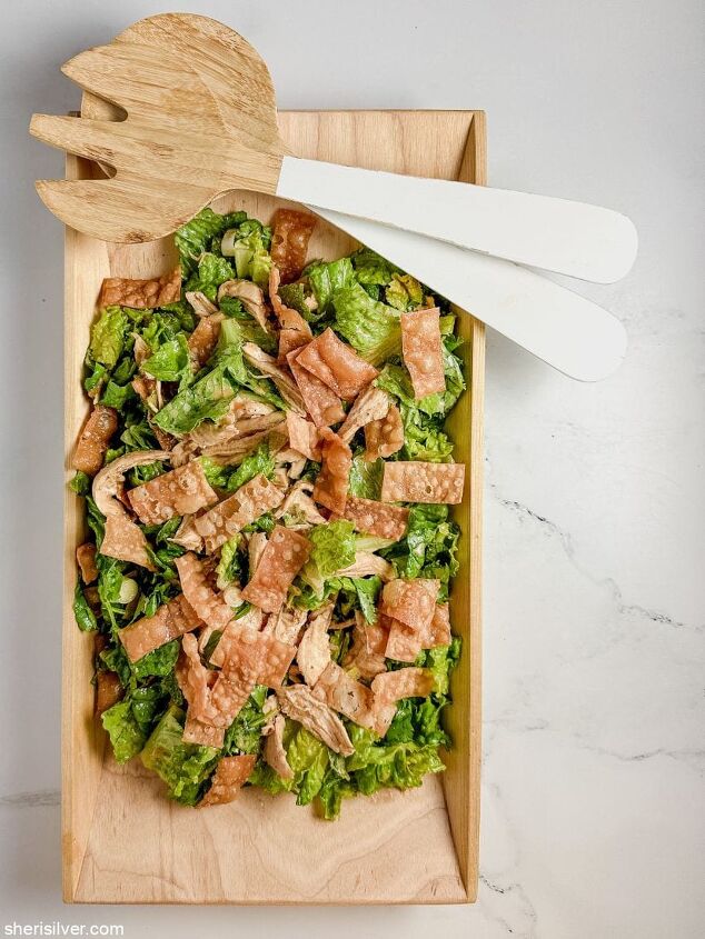 make this easy crispy wonton chicken salad recipe, crispy wonton chicken salad in a wooden serving plater with wood and white serving utensils