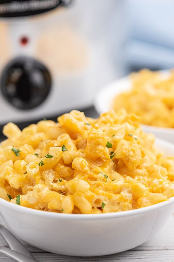 awesome slow cooker macaroni cheese with just 5 ingredients, bowl of mac and cheese in serving bowl with slow cooker in background