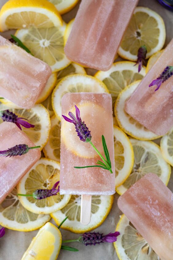 lavender gin lemonade popsicles, Six Lavender Gin Lemonade Popsicles in a circle topped with fresh lavender flowers and laying on a bed of fresh lemon slices